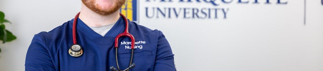 Nursing student standing confidently by sign