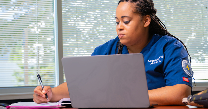 Marquette nursing student sitting at desk using laptop